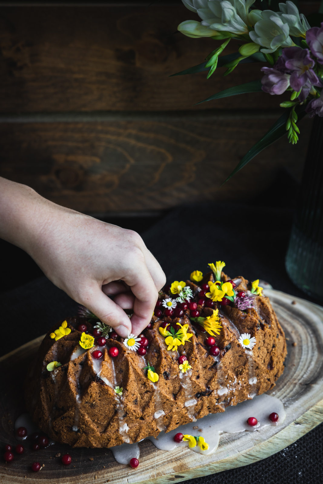 Vegánsky brusnicový koláč si môžete ozdobiť citrónovou polevou, brusnicami a jedlými kvetmi. 