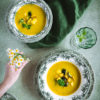 Vegánska cuketová krémová polievka servírovaná v rustikálnych tanieroch so zeleným kvetinovým motívom